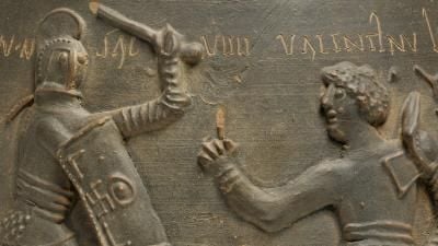 A detail from a Roman clay vase showing two gladiators fighting.