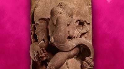 A stone statue of the elephant-headed god Ganesha on a bright pink background