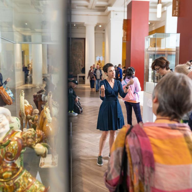 Volunteer explaining objects to a group of Museum visitors