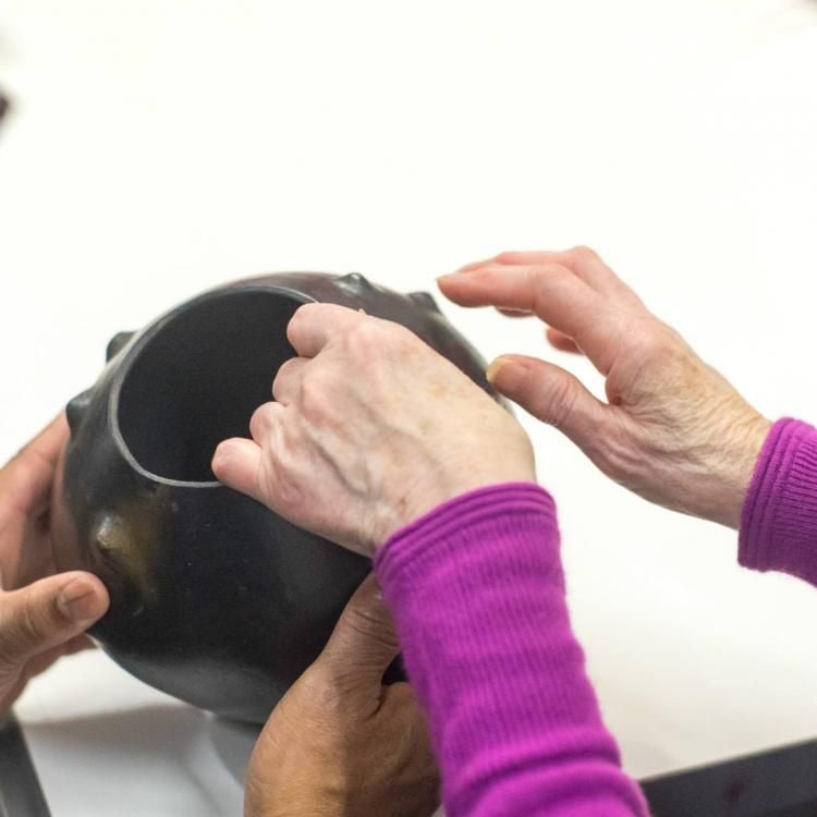 Two people handling a pot at a South Africa object handling session. 