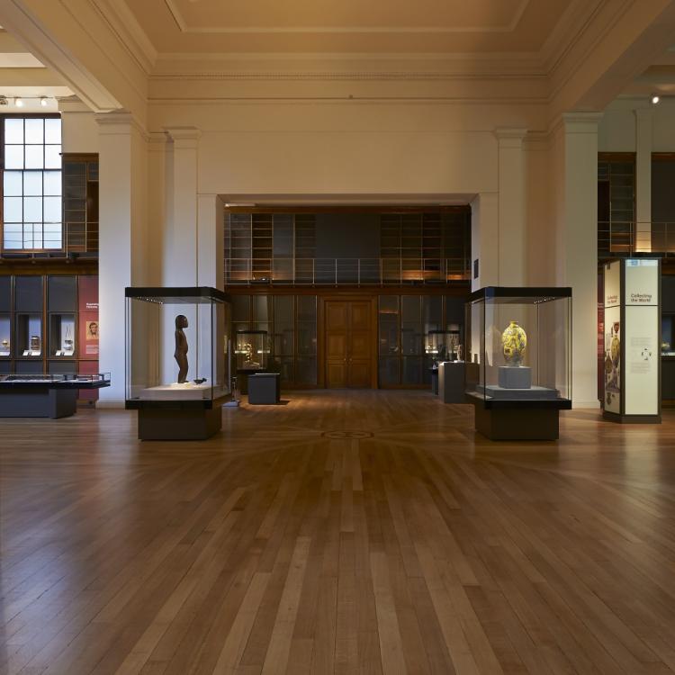 Image of a gallery wooden floor and objects in cases, statues