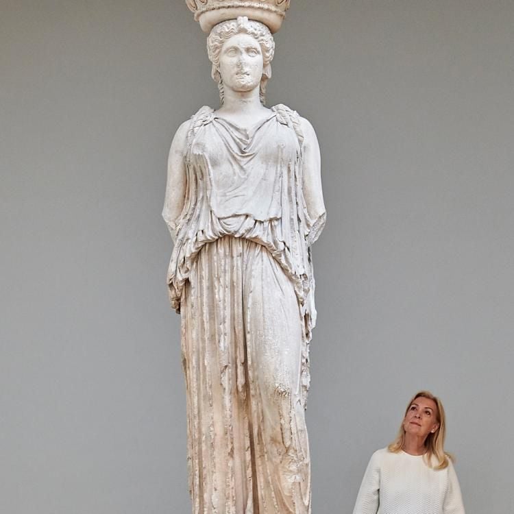 A visitor standing next to the statue of Athena