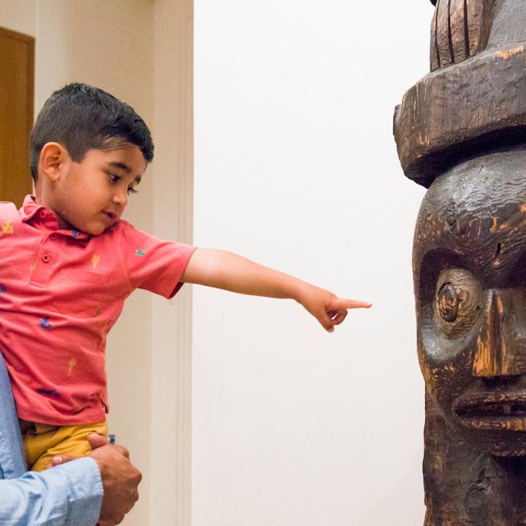 A father and son looking at the wood carving in room 26