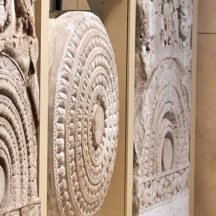 A visitor viewing a limestone Dome-slab early Buddhist sculptures from Amaravati depicting The Great Departure of Prince Siddhartha
