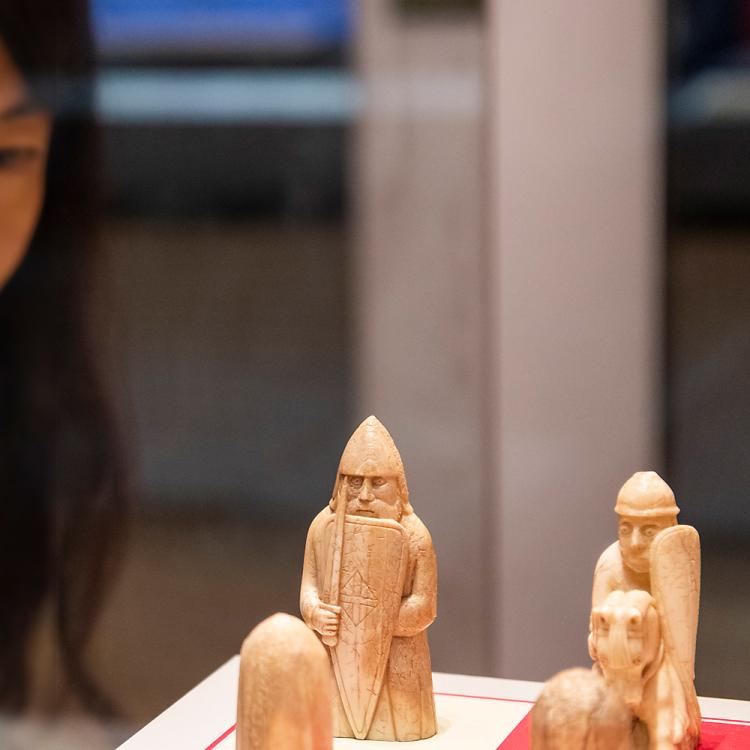 A visitor looking closely at the Lewis Chessmen in a glass cabinet