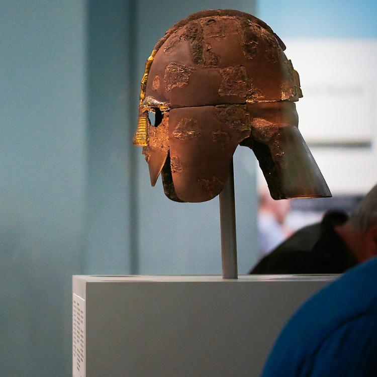Visitor looking at the Sutton Hoo helmet in Room 41