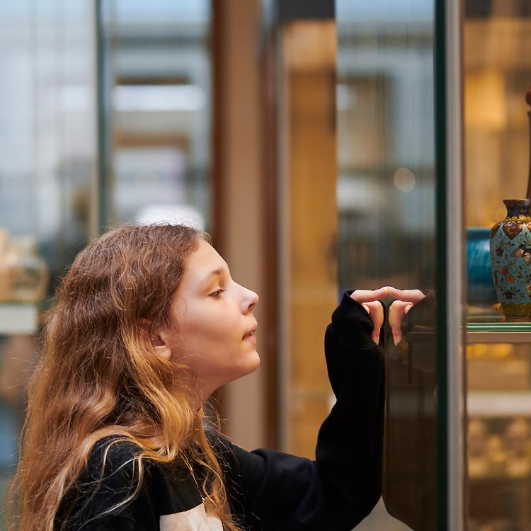 A father and daughter looking inside a display cabinet. The daughter points at the objects inside the cabinet