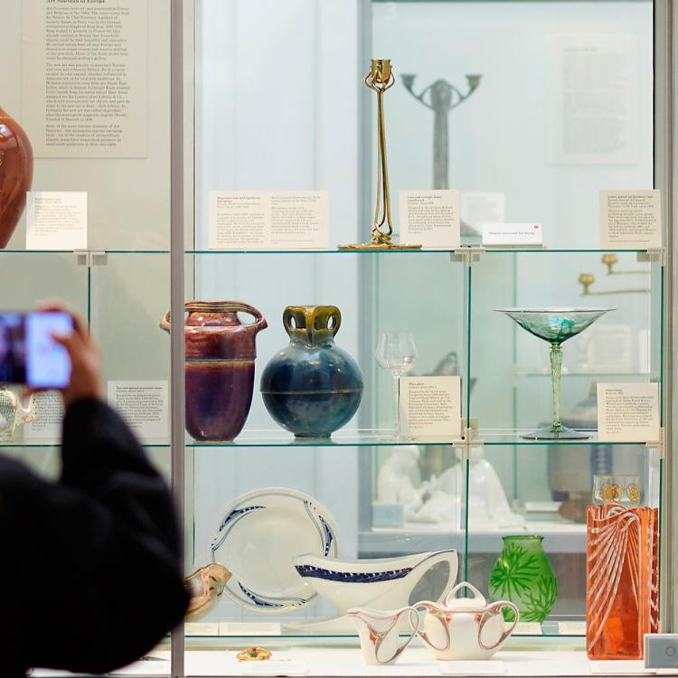 A visitor photographs room 48. Differently coloured objects are on display