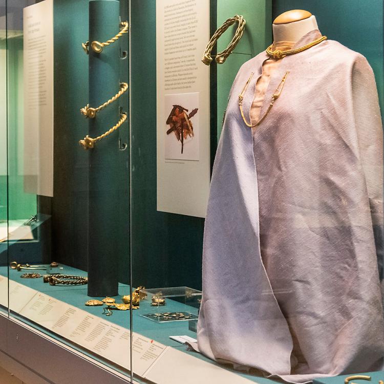 A visitor examines the clothing and royal jewellery in Room 50