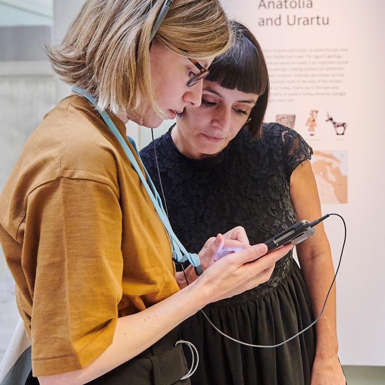 Two female visitors looking at an audio guide in room 54