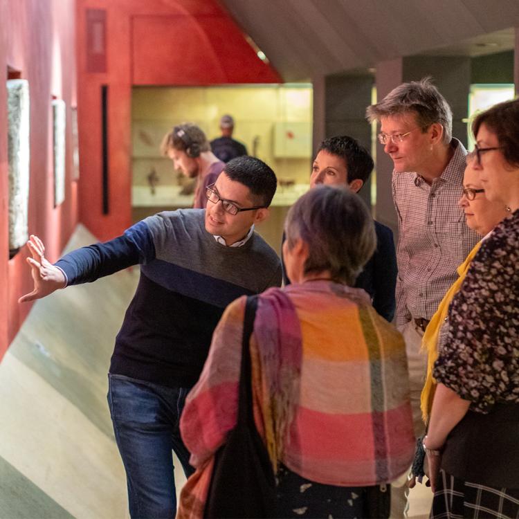 A tour group looking at lintel carvings in the Mexico gallery.