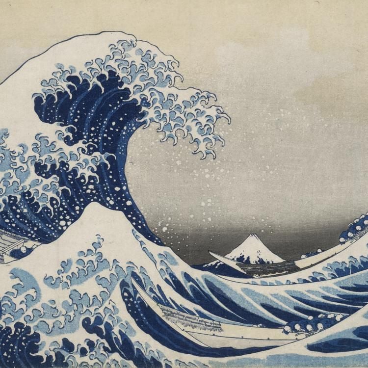Print of a large blue wave with lots of white spray. Rowing boats in the water in the foreground below the wave, and a view of Mt Fuji in the background.