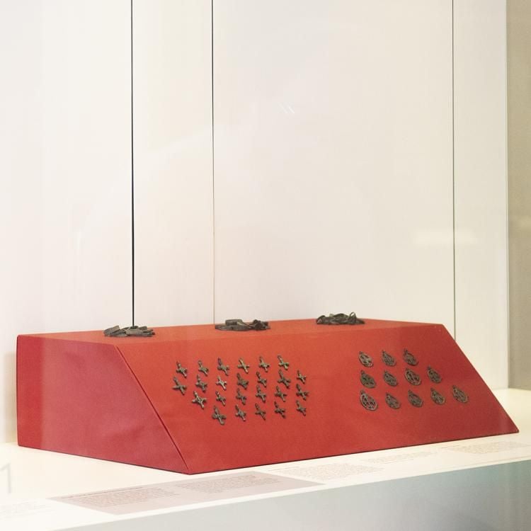 A person looking into a case of metal crosses.