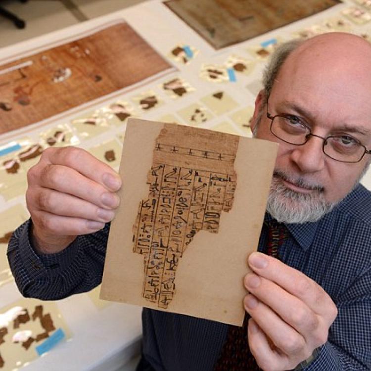 A man holds up a fragment of manuscript