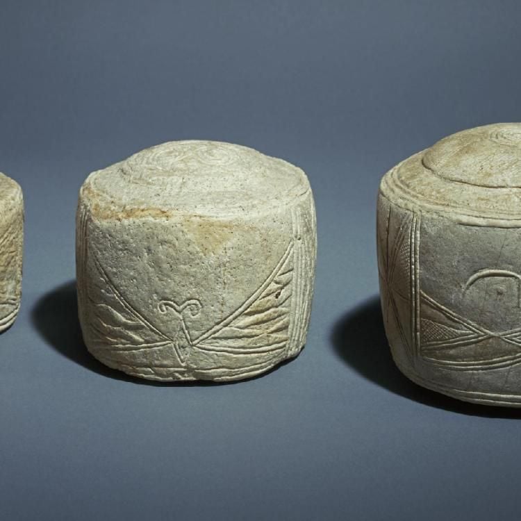 Three chalk drums with carved decoration. The smallest on the left, followed by a medium sized drum in the middle and a large drum on the right.  