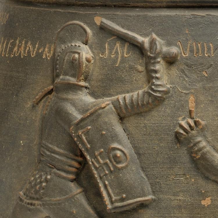A detail from a Roman clay vase showing two gladiators fighting.