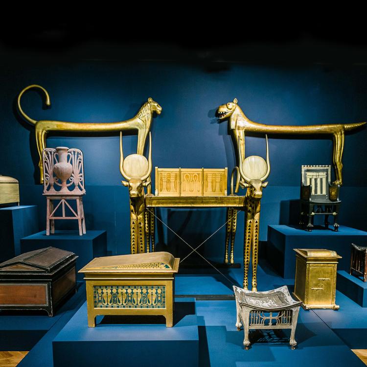 Ancient Egyptian artefacts, including furniture and chests displayed on a blue background 