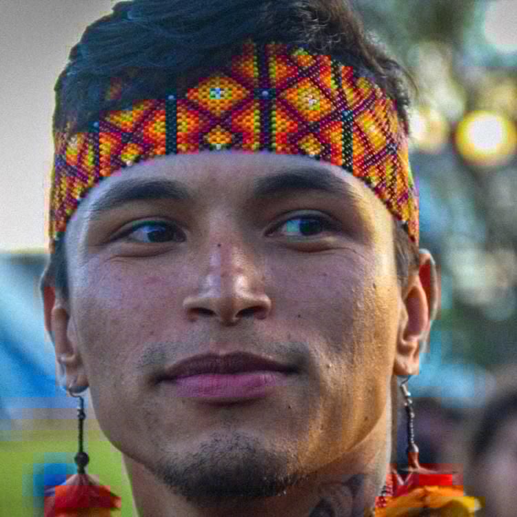 Ykaruni Nawa wears a colourful headband and earrings adorned with colourful feathers