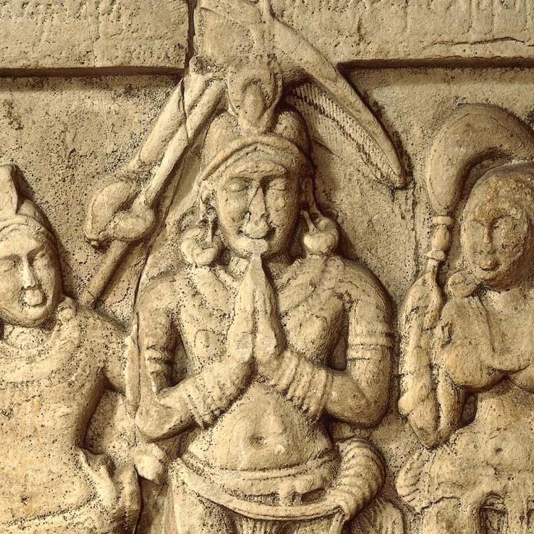 Limestone carving of the Buddha flanked by four figures