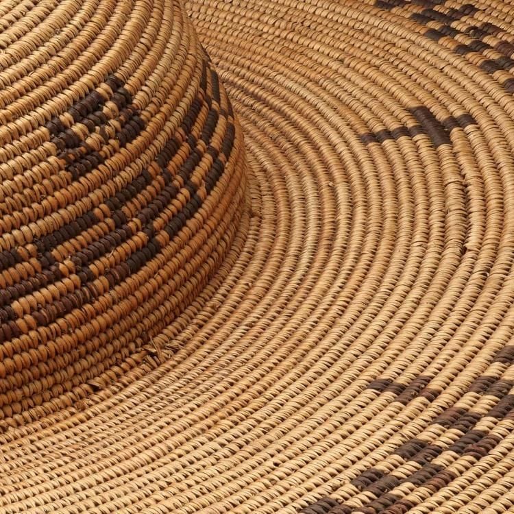 Handwoven basketry hat in a straw colour with a darker graphic pattern and crosses
