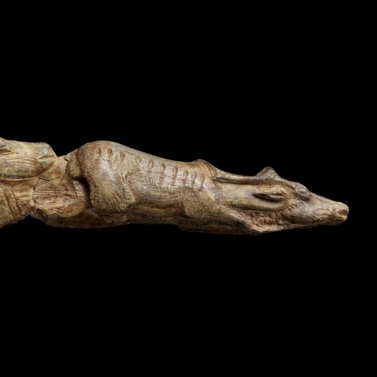 Long slender carving depicting one reindeer leading another through high water.