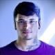 Ykaruni Nawa wears glasses, a purple tshirt and has a tattoo on his neck