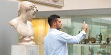 A visitor photographing himself next to a bust in room 70