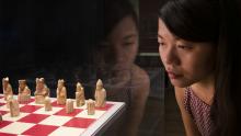 Woman looking at the Lewis Chessmen on a red and white chessboard.