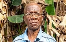 Headshot of Adebayo Folorunso outside, foliage behind