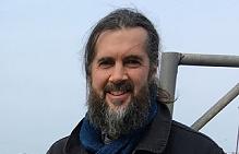 Headshot of Sam Nixon outside, sky behind