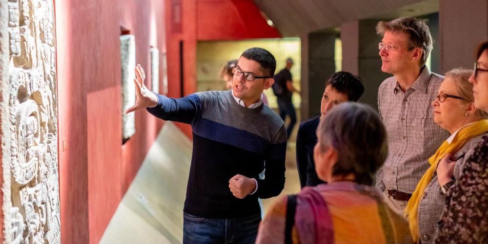 Volunteer explaining object to a group of Museum visitors