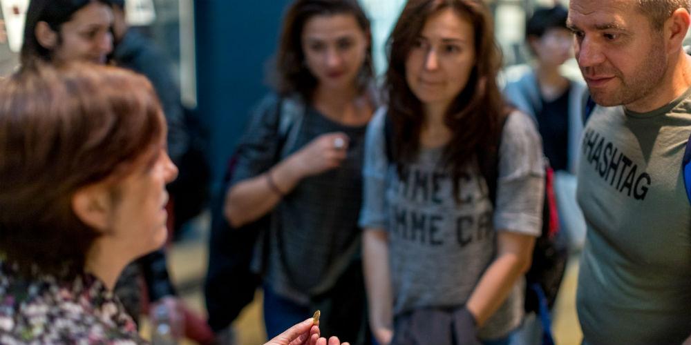 Volunteer explaining coin to group of Museum visitors