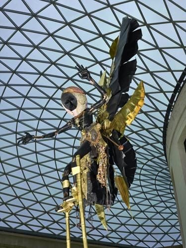 Steel sculpture; male figure of a stilt-walker (Moko Jumbie). Figure has articulated limbs, painted black. Wears a loincloth composed of plastic and synthetic fibres, decorated with mesh synthetic fibre vest; metal keys, bells and toy aeroplane; plastic beads; wooden masks. 