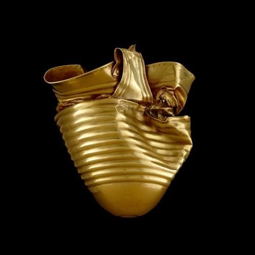 Gold cup, body beaten out from single piece of metal. With sub-conical body tapering to an omphalos base; the rim is flaring; the single rivetted strap handle links the rim to the mid carination.