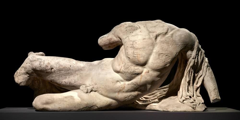 White male sculpture lying naked on one side, head, hands and feet removed. 