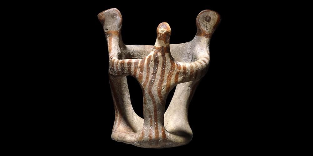 Greek terracotta figure of three dancers joined together in a ring.