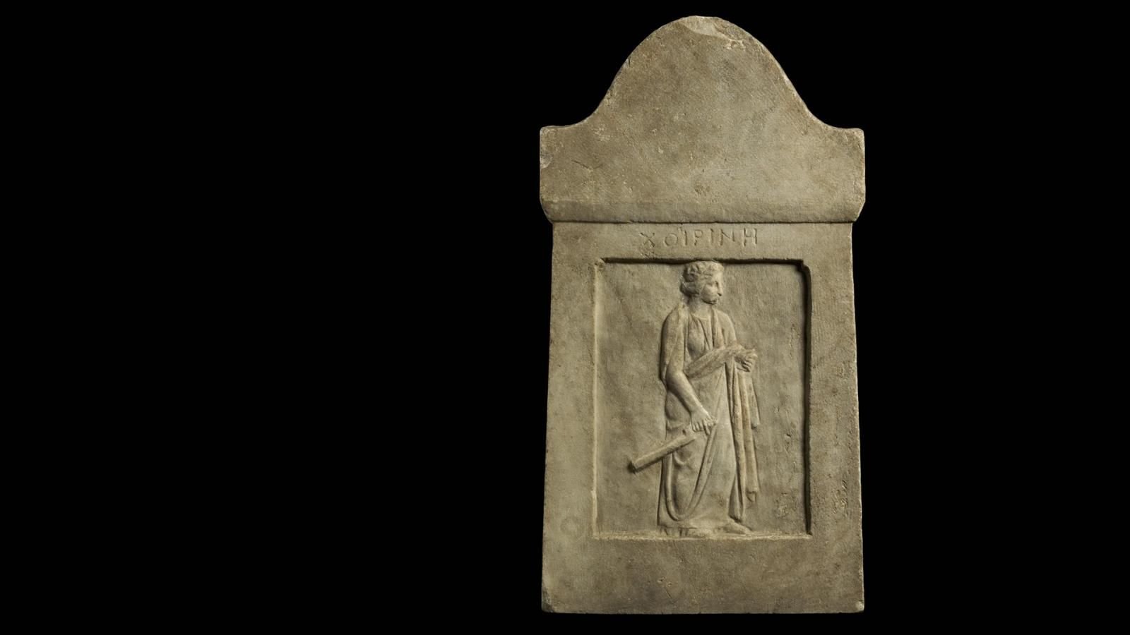 Marble grave stela of a priestess wearing a sleeved chiton, peplos, and a himation, holding a large temple key.