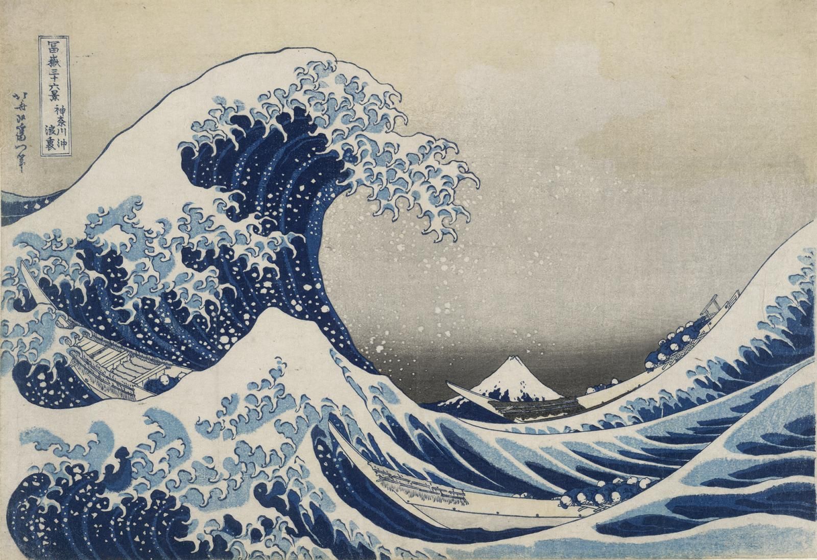 Print of a large blue wave with lots of white spray. Rowing boats in the water in the foreground below the wave, and a view of Mt Fuji in the background.
