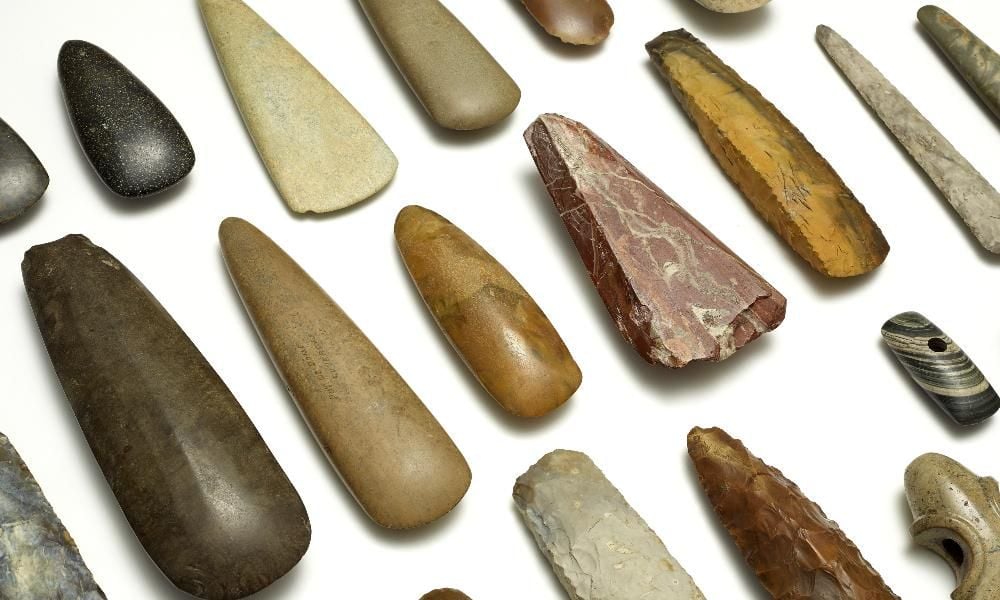 A group of different coloured stone axe heads. 