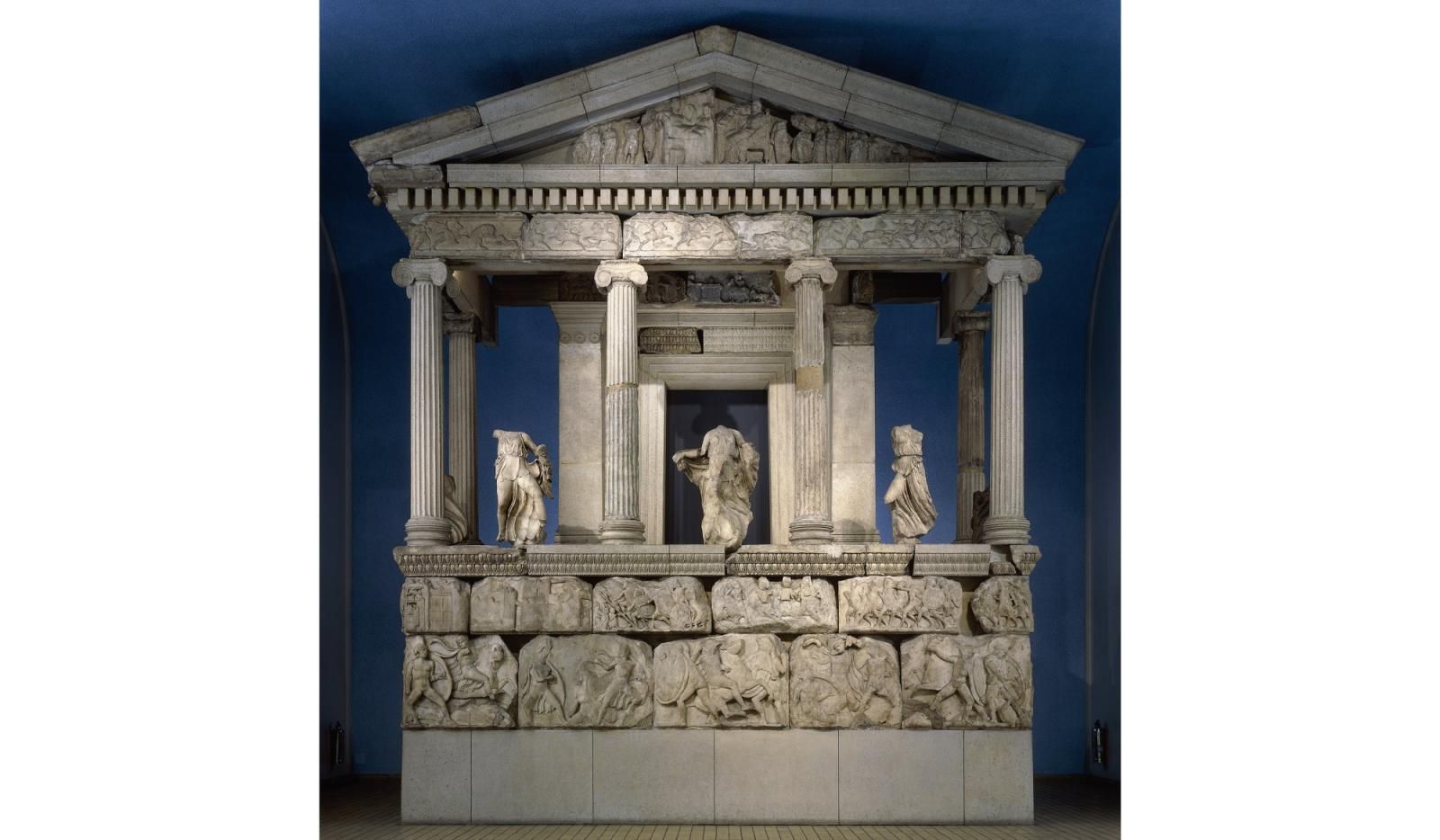 A large marble Greek temple with three human figures. 
