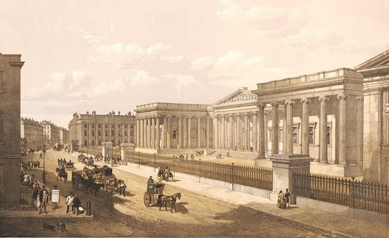 A drawing of the entrance of the British Museum during the Victorian era. n iron railing separating forecourt from street; carts and carriages travelling down street with pedestrians on either side.