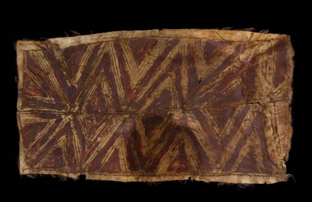 A rectangular piece of brown cloak with red pigment pattern. 