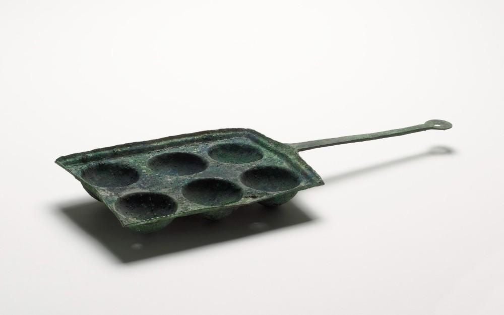 Bronze baking pan with handle and six round indentations for cake and bread dough