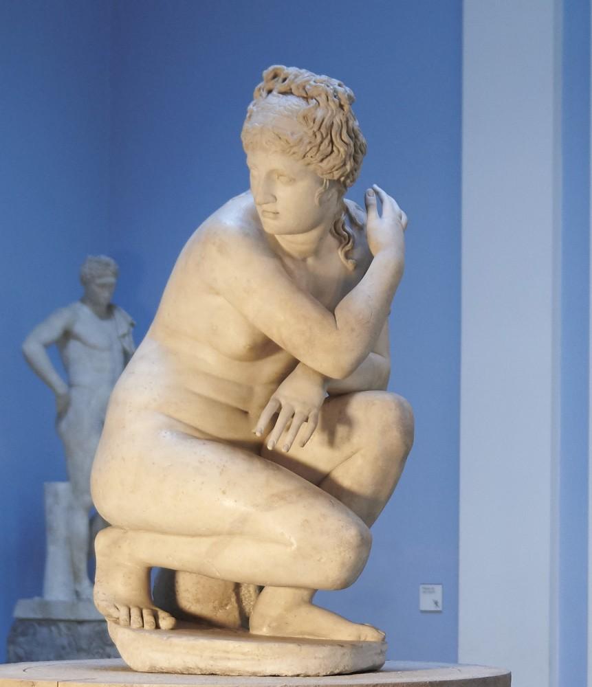 Marble statue of naked female crouching, looking to one side