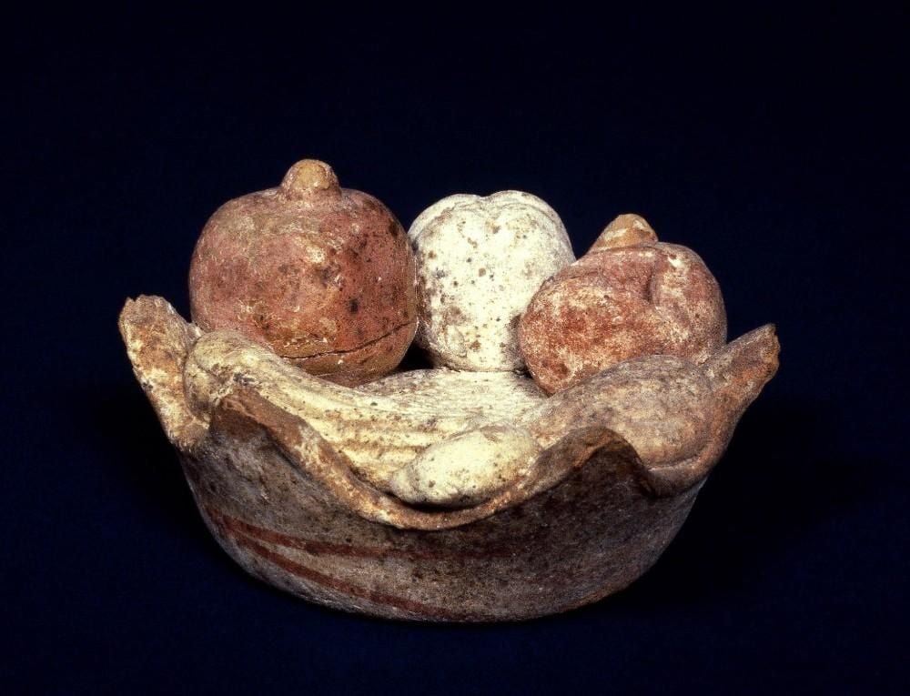 Terracotta model of a basket containing various fruits (a pomegranate, an apple, a fig, an almond and a small marrow), coloured red and white