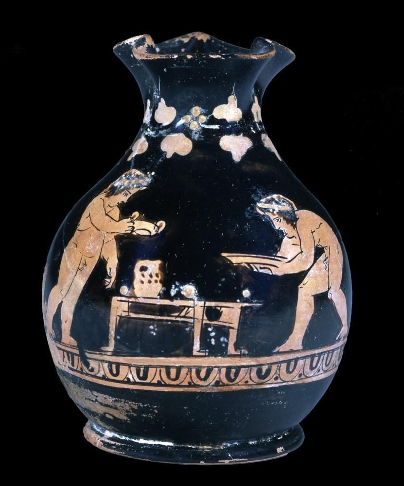 Vase showing two boys either side of a table, one stooped holding dish