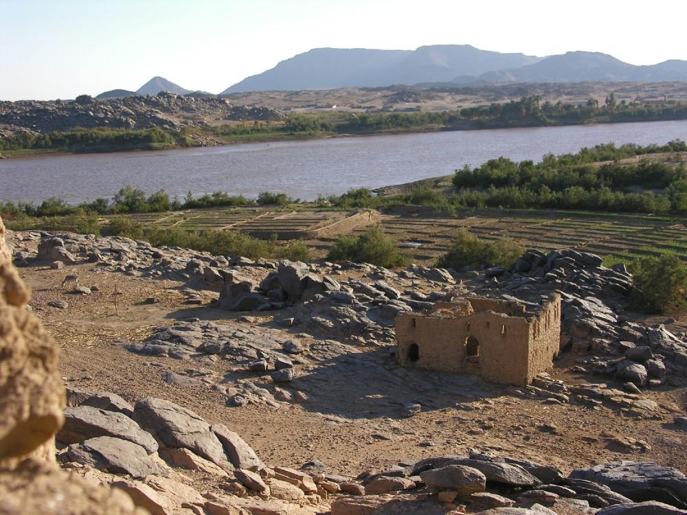 Remains of church in rocky landscape with river behind and mountains in background