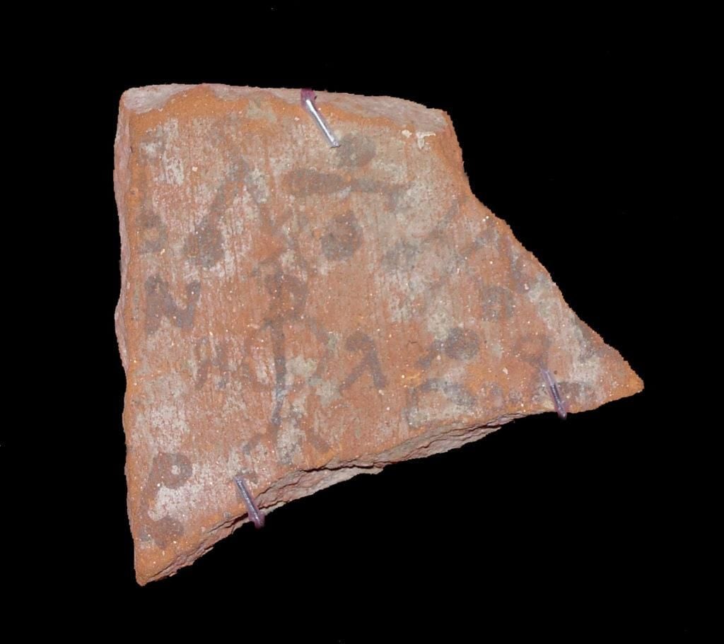 Photograph of a pot shard from a ceramic bowl. The shard is decorated with magical symbols and the monogram of the archangel Raphael (now very faded)