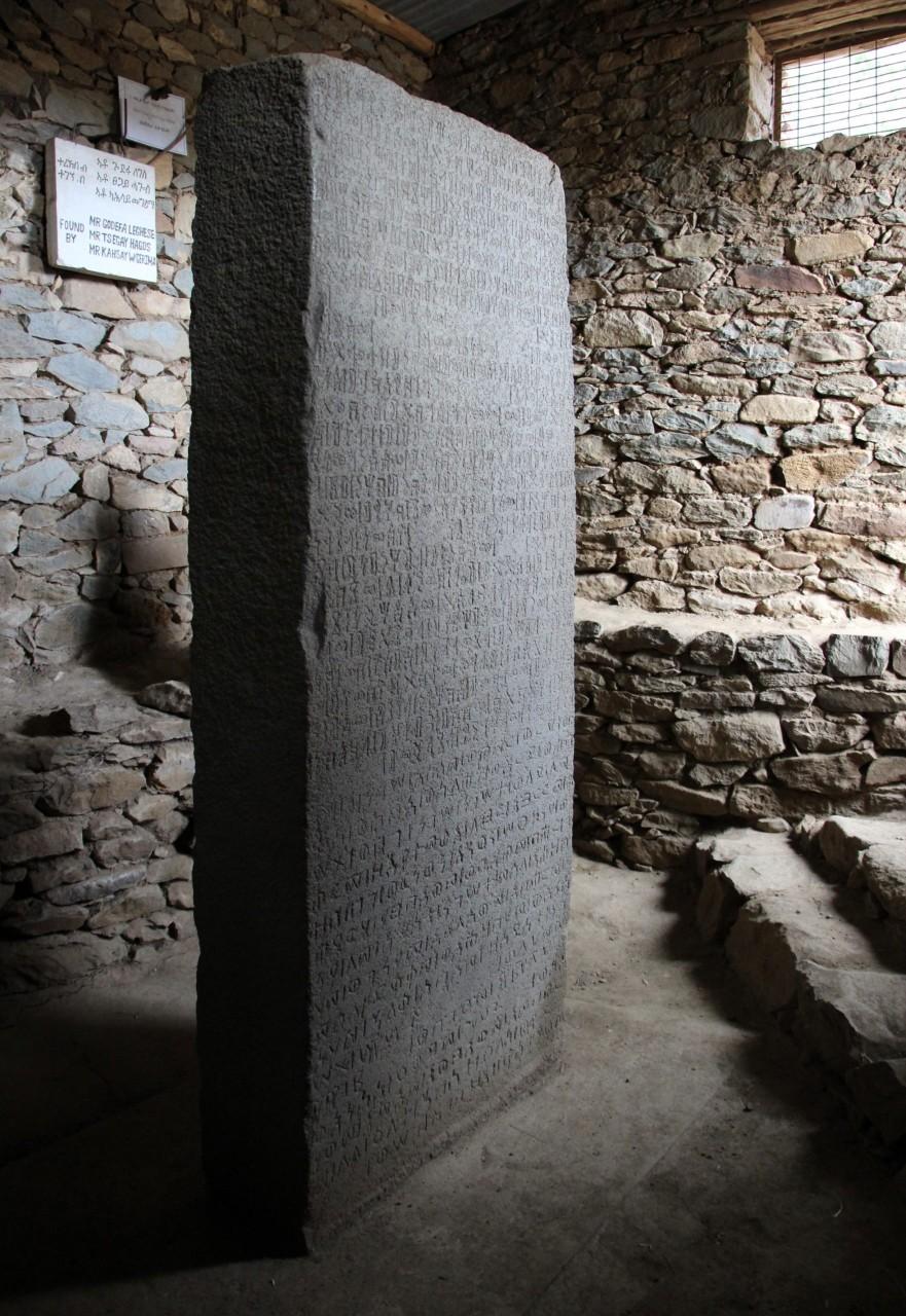 Large standing stone with inscription inside stone-brick building