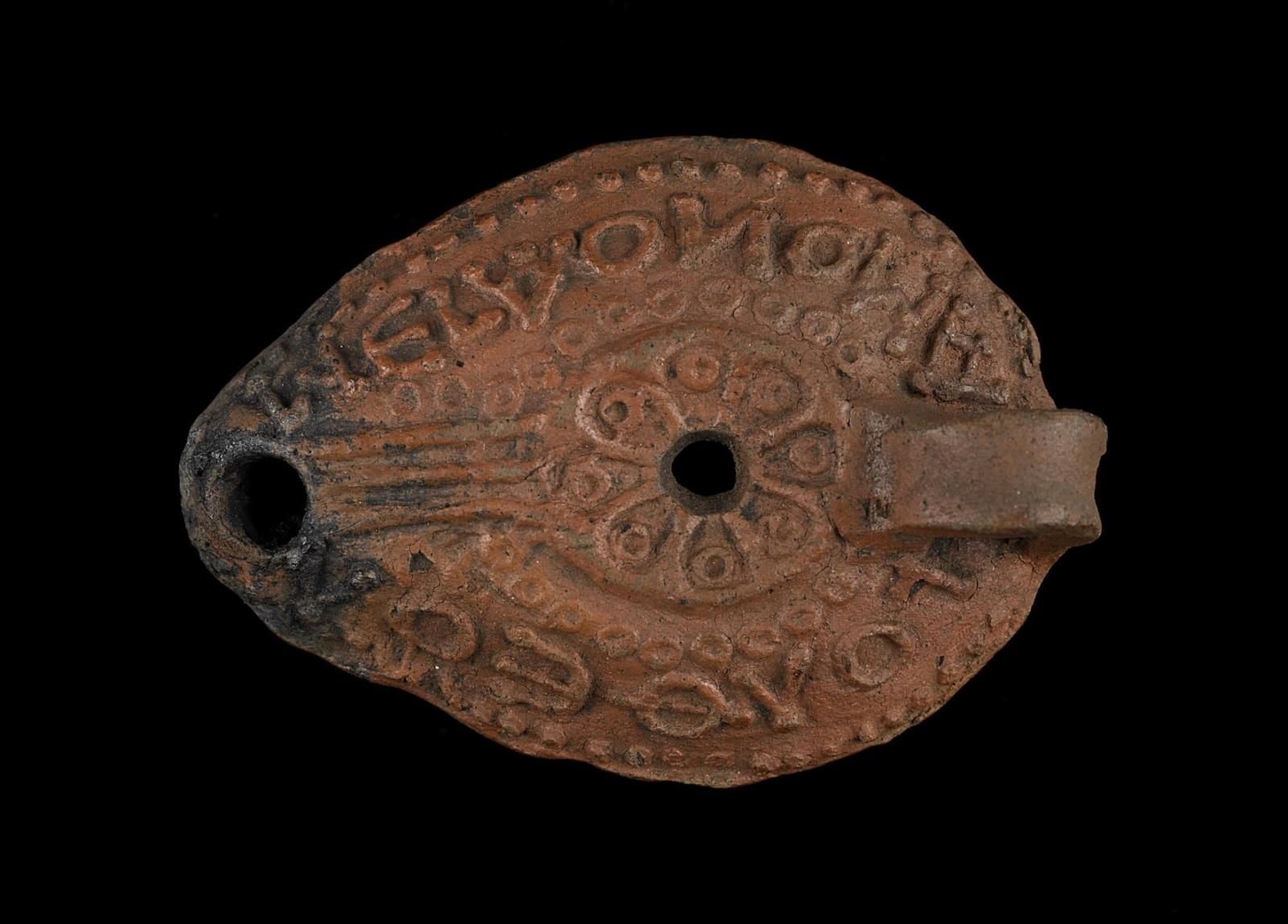 Pottery lamp pictured from above with inscription and decoration